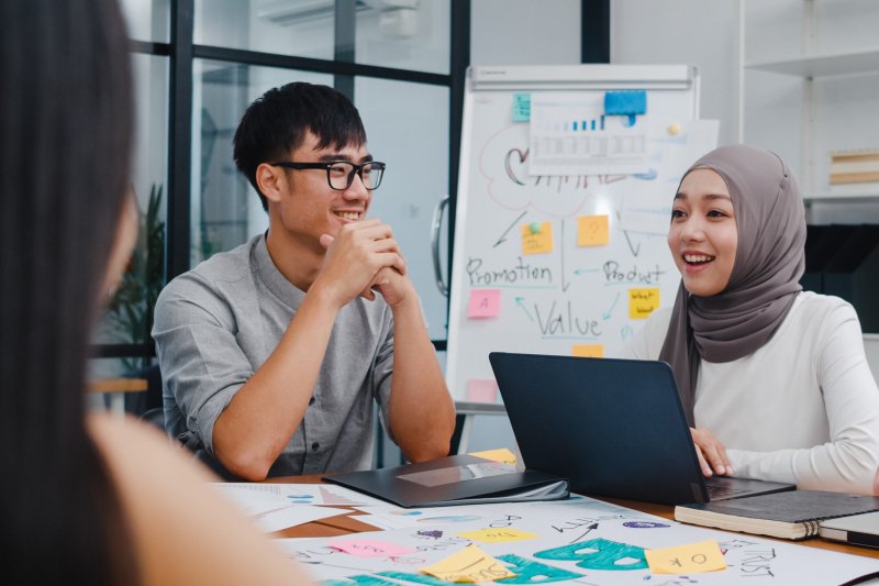 Multiracial group of young creative people in smart casual wear discussing business brainstorming meeting ideas mobile application software design project in modern office. Coworker teamwork concept.